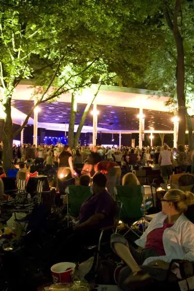 Festival goers sitting and standing over the lawn enjoying music