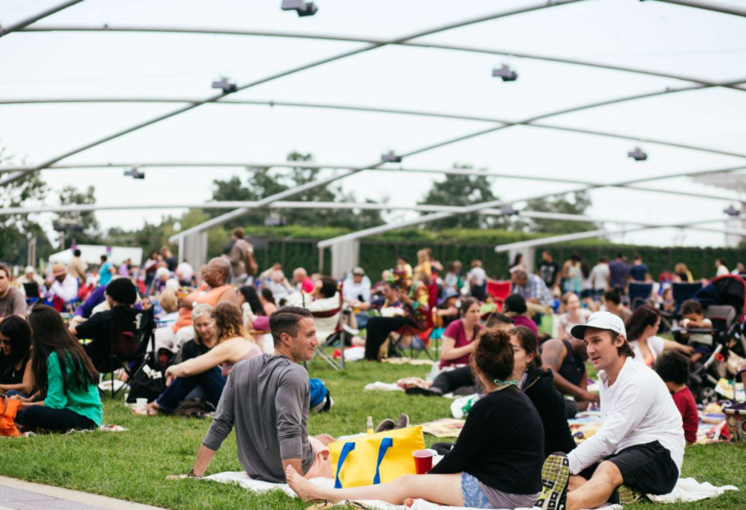 A large audience sitting on the grass outside the Pritzker Pavillion