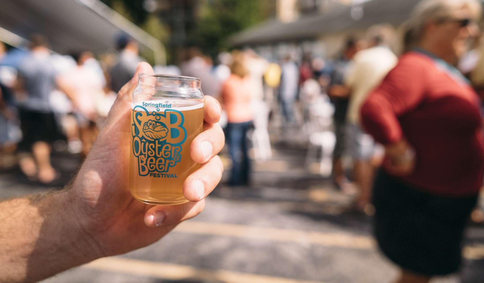 Someone holding a Springfield Oyster and Beer Festival branded jar, full of beer