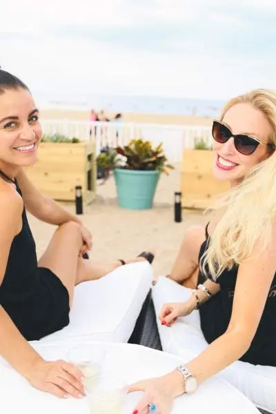 Two women enjoying a drink on a beach lounger