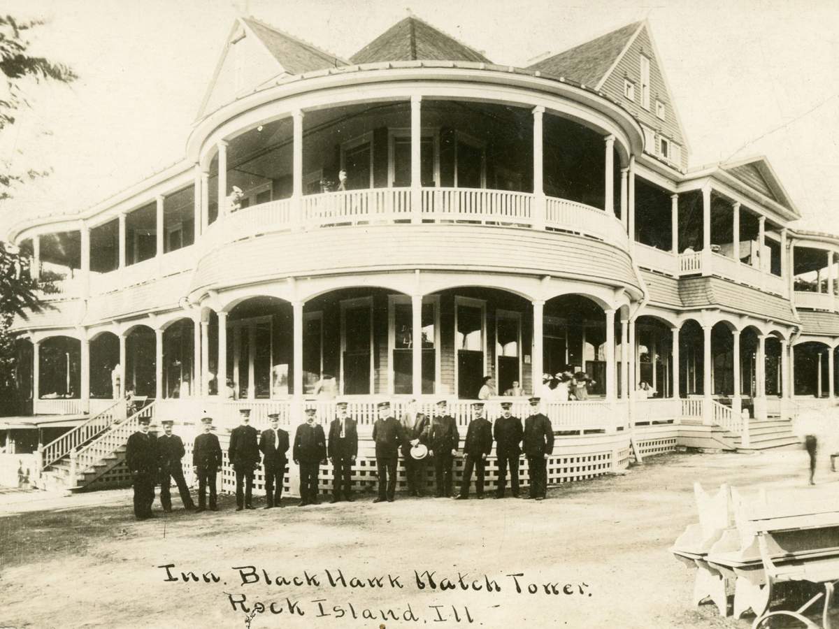 An old black and white photo of a group of men standing in front of a wooden building