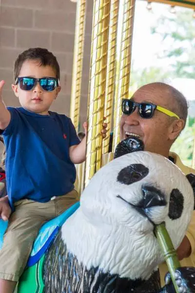 A toddler and his grandparents on the carousel at the Brookfield Zoo.