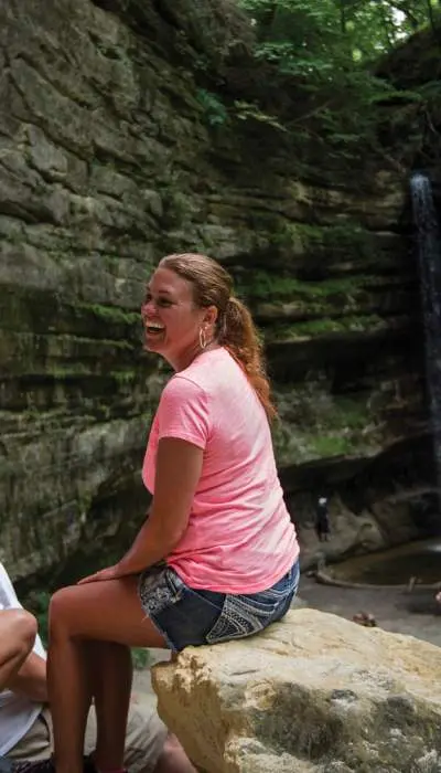 A family of four sitting down for a rest on rocks in front of a waterfall