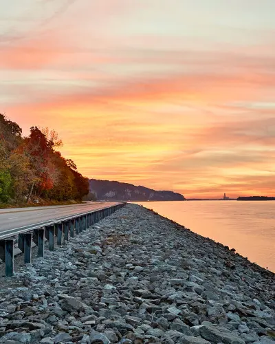 Sunset shining over water and a road beside the river