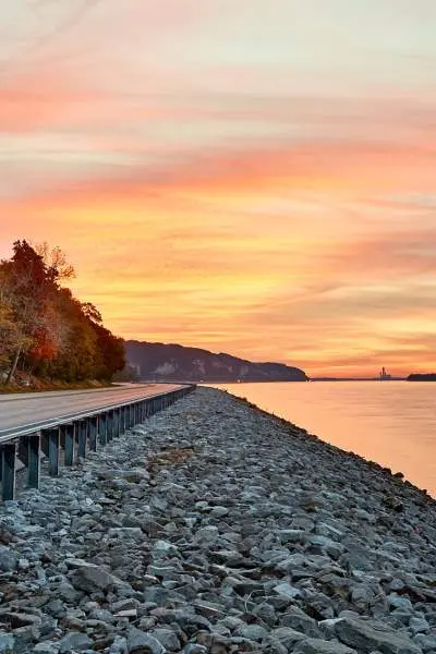 Sunset shining over water and a road beside the river