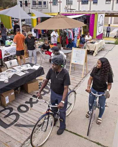 Two people on bikes in front of an outdoor market